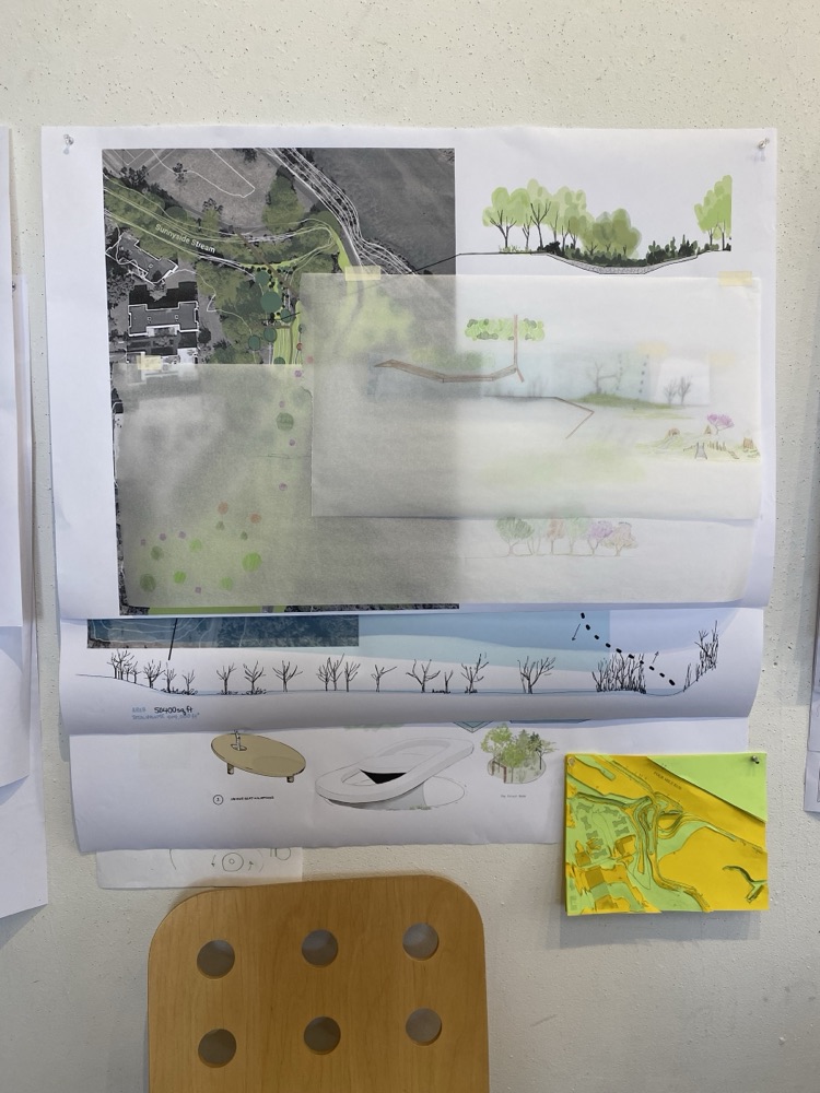 Layered site plans and landscape sections on trace paper, pinned to a wall