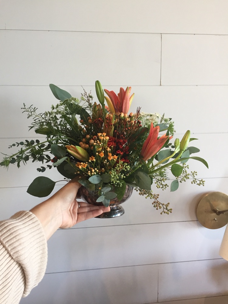 Arrangement of lilies and berries in a silver footed bowl