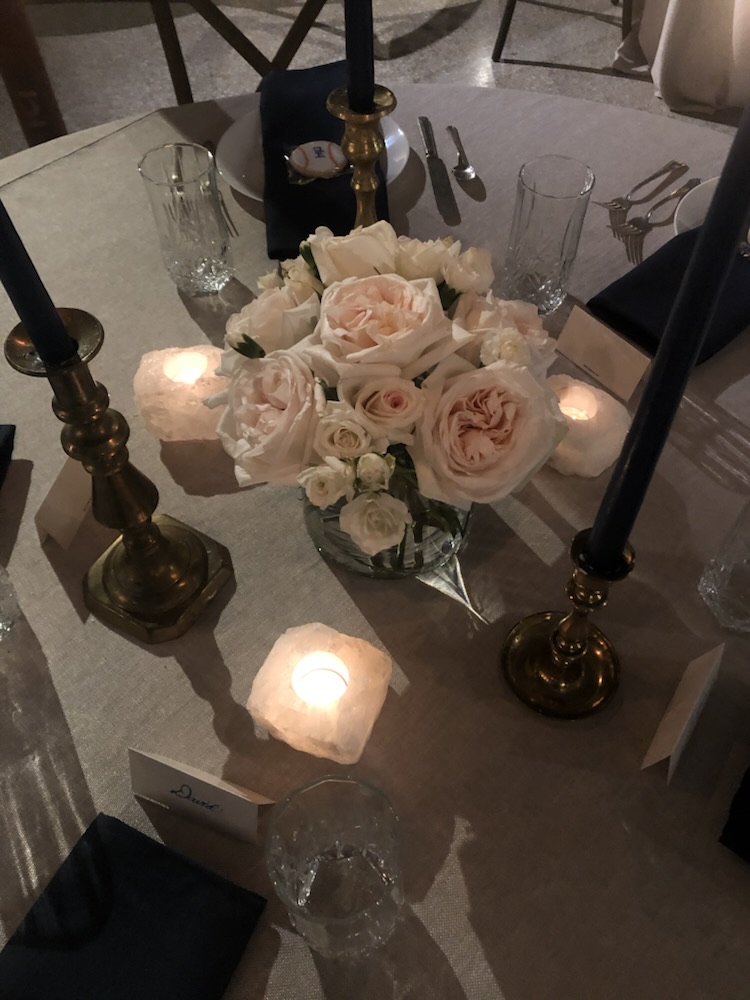 Blush roses between brass candlesticks at a candlelit table