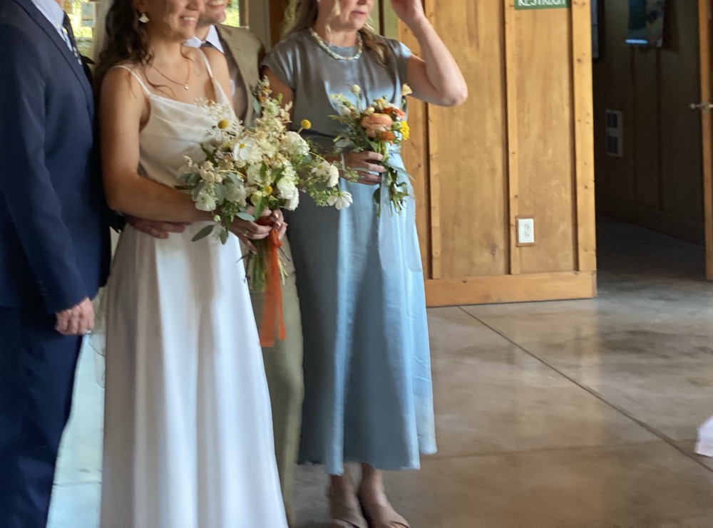 Bride and family holding wildflower bouquets at a barn wedding